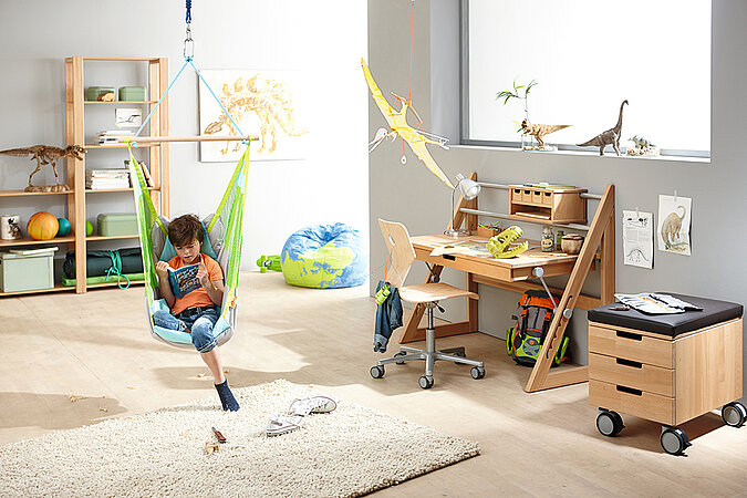 Ein Kind sitzt im Kinderzimmer in einem Hängesessel und liest