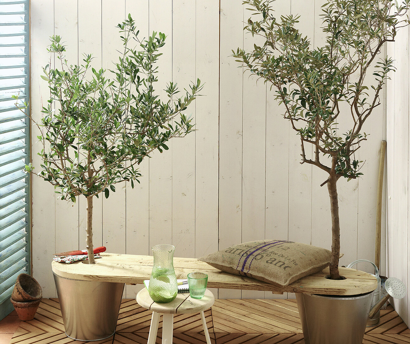 DIY-Gartenbank aus hellem Holz, 2 Blumenkübel dienen als Halterung für die Sitzfläche