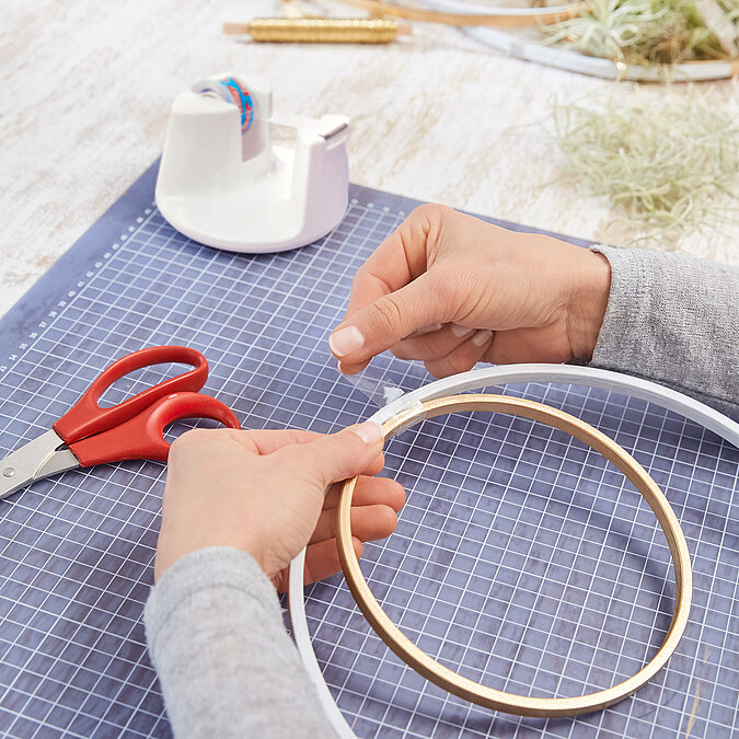 Wanddeko mit Pflanzen an der Wand befestigen, Einhängen eines Holzrings mit Luftpflanze an transparentem Wandhaken