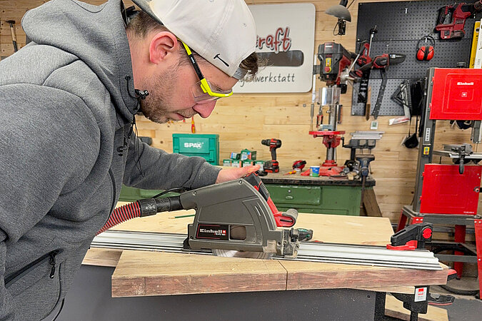 Man sägt mit einer Handkreissäge die Lehne für eine Sitzbank aus einer Gerüstbohle zu