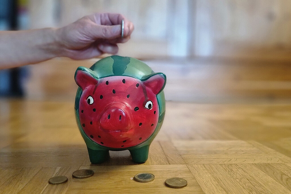 Geld ins Sparschwein werfen