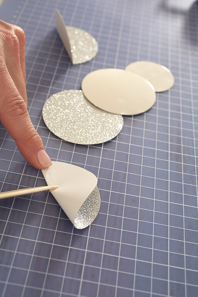 Kreise aus papier werden mittig gefalzt, die Glitzerseite liegt dabei innen