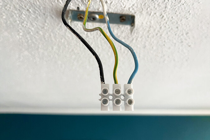3 Kabel zum anschließen an eine Leuchte kommen aus der Decke - Die kabel haben die Farbe schwarz, gelb und blau befinden sich in einer Lüsterklemmer