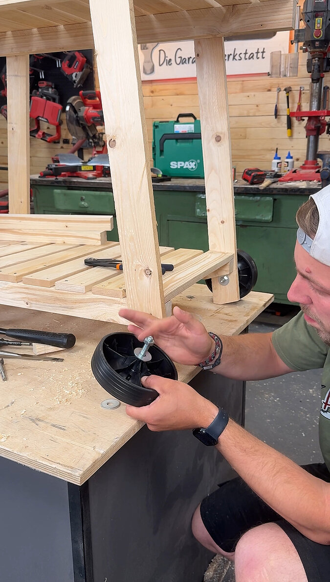 Mobilen Grillwagen bauen beim Anzeichnen der Bohrlöcher für die Lenkrolle, Vorbereitung der Rollenmontage am Holzrahmen des mobilen Grillwagens