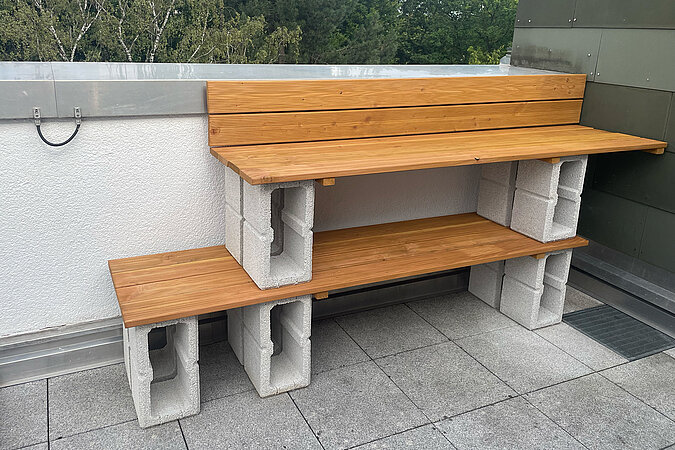 Grillplatz für die Terrasse bauen: Fertig aufgebaute DIY-Grillstation aus Betonsteinen und geölten Holzbohlen mit seitlicher Ablage – funktionales Outdoor-Möbel für Grillabende auf Balkon oder Terrasse.