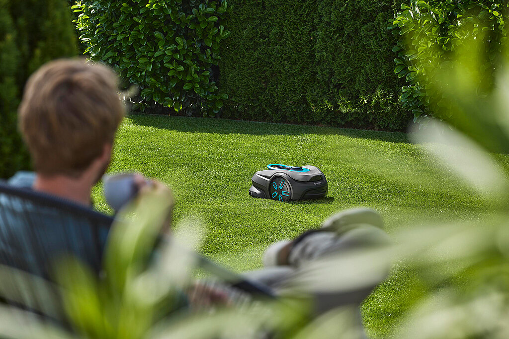Mähroboter schneidet gleichmäßig den Rasen vor moderner Terrasse mit entspannter Gartenatmosphäre