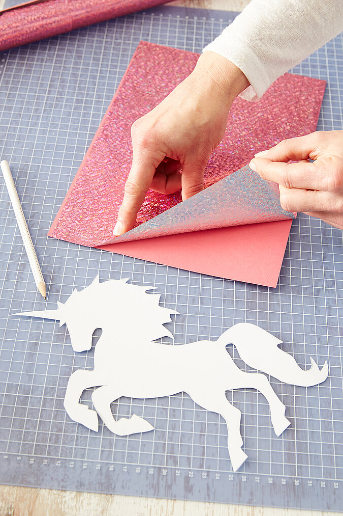 Für eine Schultüte wird ein Einhorn aus glitzernder Folie ausgeschnitten