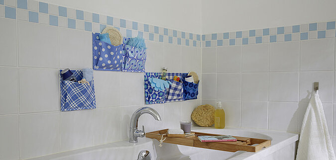 gekachelte Badezimmerwand mit blau-weissen Aufbewahrungstaschen aus Wachs