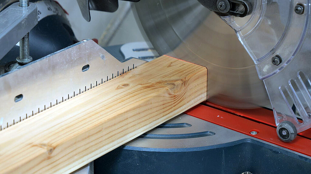Eine Holzleiste wird mit elektrischer Saege zugeschnitten