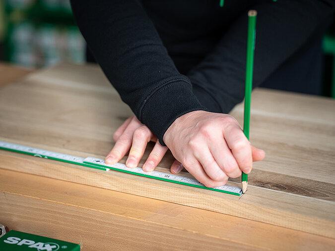 Lernturm für Kinder bauen und Holz präzise mit Zollstock und Bleistift anzeichnen für den exakten Zuschnitt