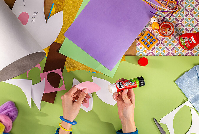 Schultüte Einhorn basteln mit Klebestift und vorbereiteten Einhorn-Ohren aus Papier
