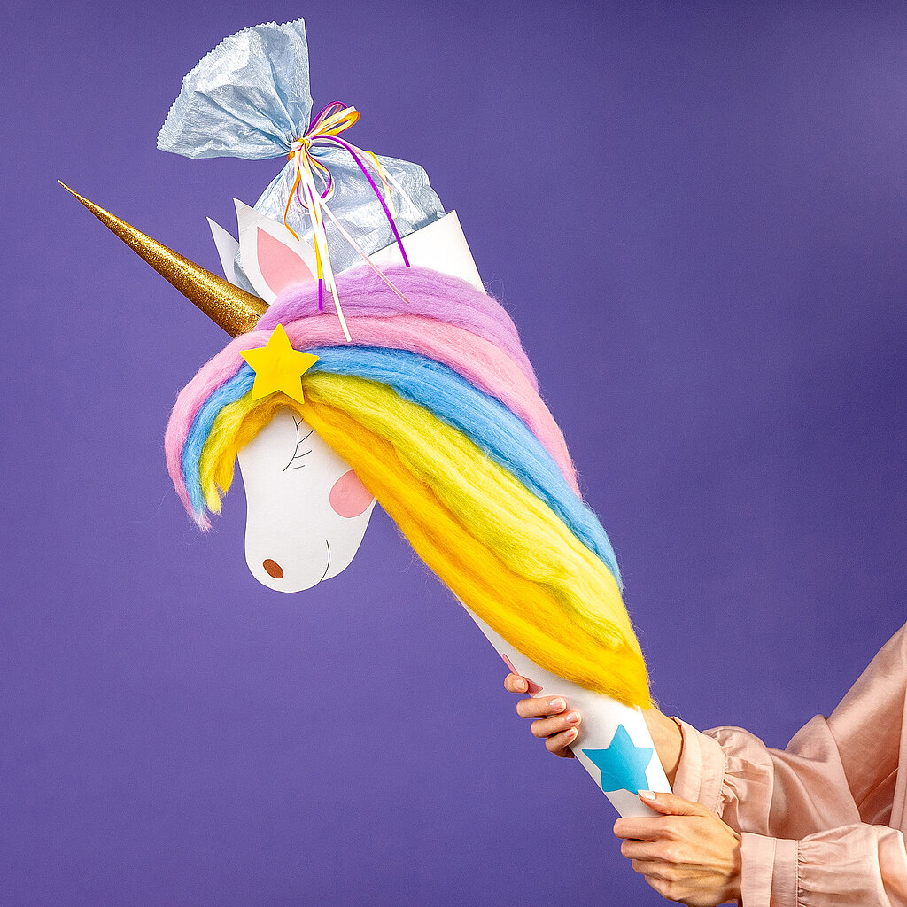 Schultüte Einhorn basteln mit fertiger Einhorn-Schultüte, goldenen Horn und bunter Regenbogenmähne