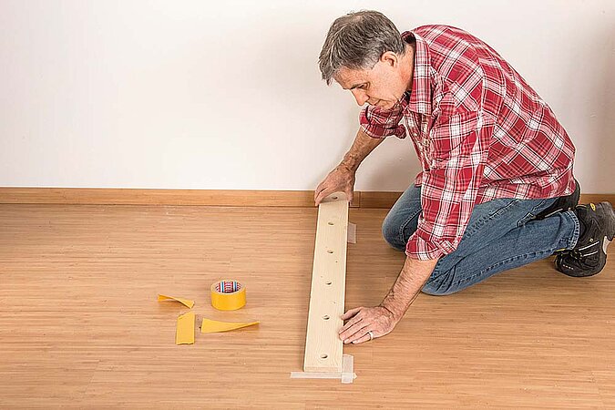 Unteres Holzbrett für den Raumteiler aus Birkenstämmen wird auf dem Boden positioniert und ausgerichtet