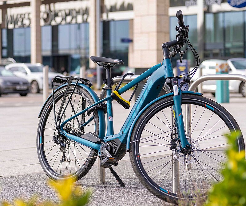 Tuerkises-Fahrrad-an-Staender-abgeschlossen
