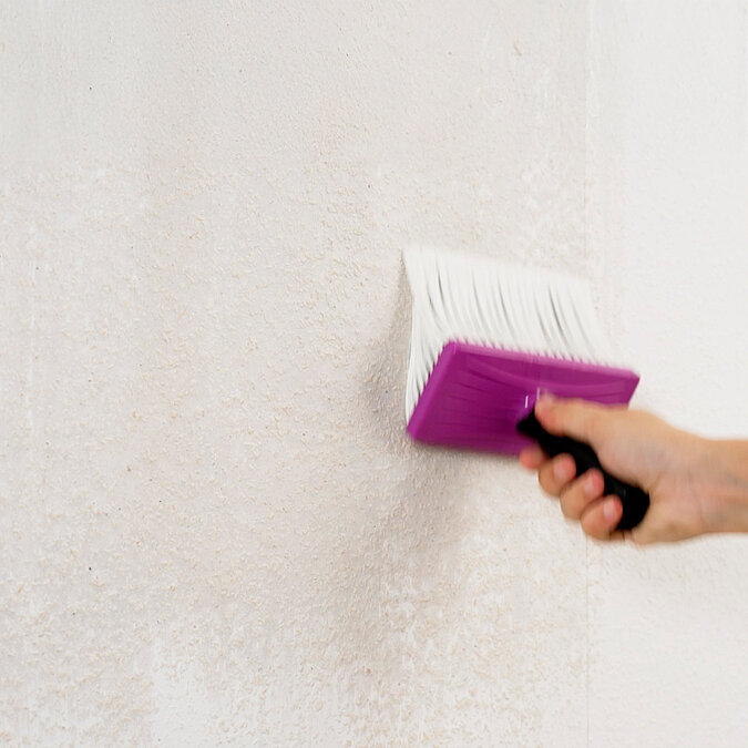 ChatGPT: Wände richtig tapezieren: Kleister wird mit Tapezierbürste gleichmäßig auf die Wand aufgetragen – essenzieller Schritt für die optimale Haftung der Tapete