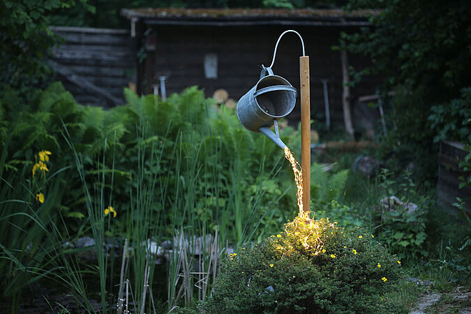 Alte Giesskanne, aus deren Tülle ein Kupferdraht mit LEDs Licht verbreitet