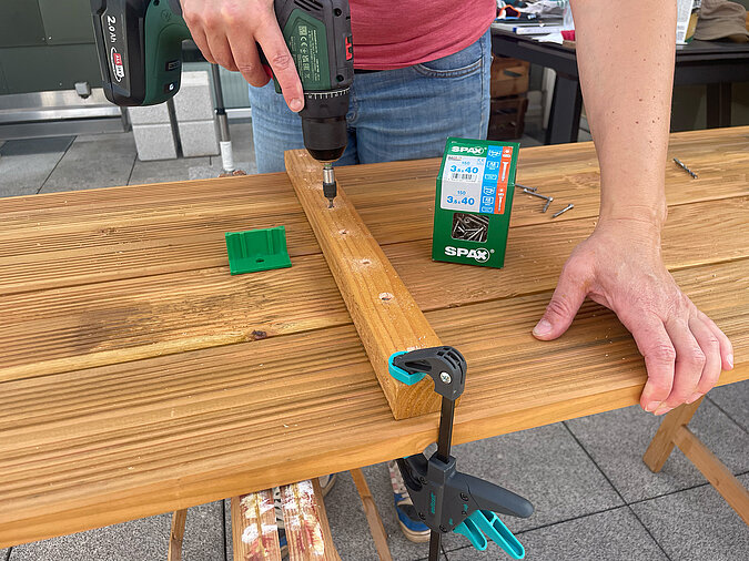 Grillplatz für die Terrasse bauen: Verschrauben der vorbereiteten Ablagebretter mit Akkuschrauber und SPAX-Schrauben – stabiler Zusammenbau für eine langlebige DIY-Grillstation im Garten oder auf der Terrasse.