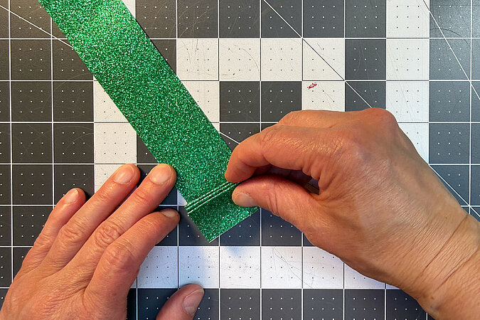 Einschulung Orden basteln mit glitzerndem Papierstreifen beim Falten der Rosette