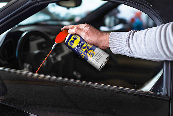Auto selbst waschen Gummidichtungen – Hand sprüht Pflegemittel auf Fenstergummis, um sie geschmeidig zu halten.