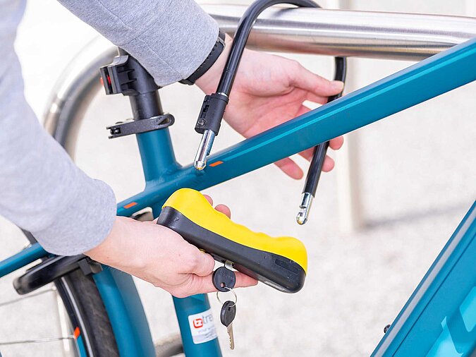 Mann-schliesst-Fahrrad-mit-Buegelschloss-ab