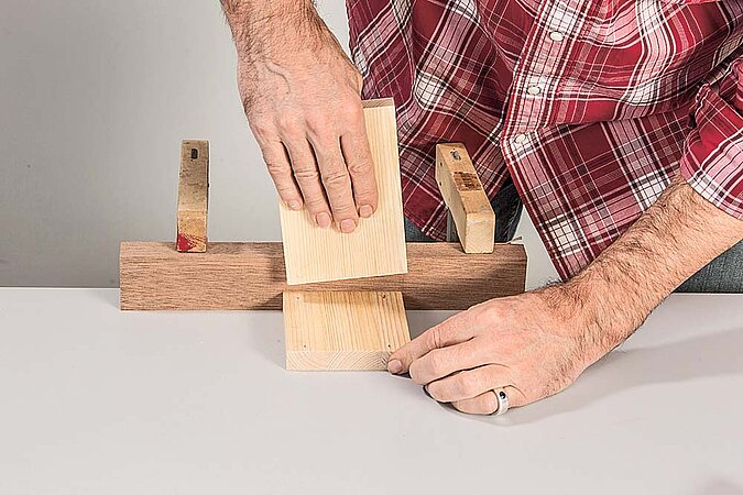 Holzteile für ein kleines Regal am Raumteiler aus Birkenstämmen werden mit Schraubzwingen verleimt