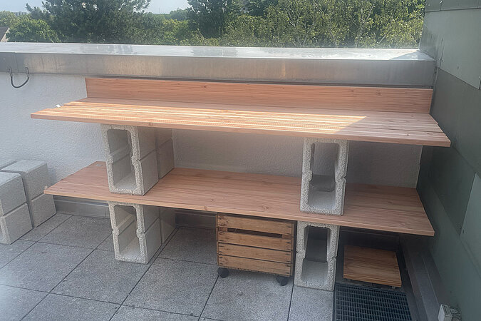 Grillplatz für die Terrasse bauen: DIY-Grillstation aus Holzbohlen und Hohlblocksteinen mit zwei stabilen Ebenen – praktische Bauweise für eine wetterfeste Outdoor-Küche oder Arbeitsfläche auf der Terrasse.
