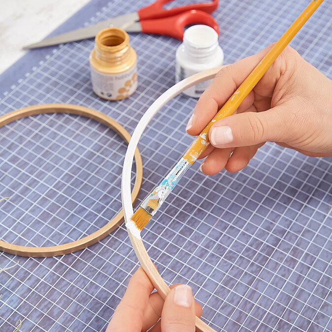 Wanddeko mit Pflanzen als Materialübersicht, Holzringe, Garn, Schere und Luftpflanzen für ein kreatives DIY-Projekt vorbereitet
