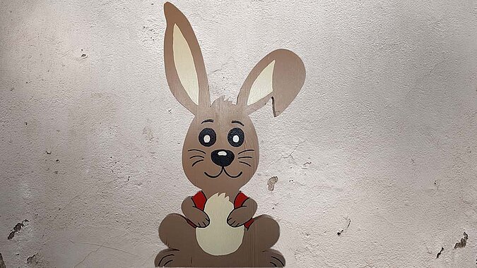 Osterhase aus Holz vor Betonwand