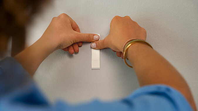 Frau hängt Bild mit Klett-Klebepads an die Wand
