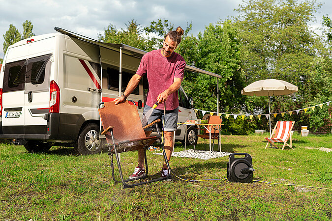 Festival Gadgets kompakter Hochdruckreiniger beim Reinigen eines Grills neben Van auf dem Campingplatz