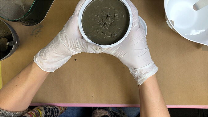Türstopper aus Beton selber machen – mit Beton gefüllte runde Form wird mit beiden Händen gehalten, gleichmäßiger Guss für einen selbstgemachten Beton-Türstopper