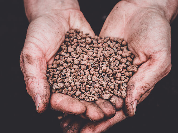 Gärtnern ohne Torf mit mineralischem Tongranulat, Hände halten strukturstabile Zuschlagstoffe zur Verbesserung von Drainage und Bodenbelüftung