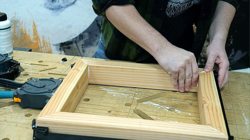 Heimwerker verleimt einen Holzrahmen in dem spaeter ein Kuebel befestigt werden soll