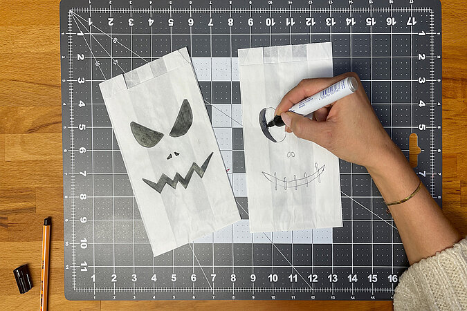 Tischdeko zu Halloween: Bestecktüten aus Butterbrotpapier mit aufgemalten Fratzen