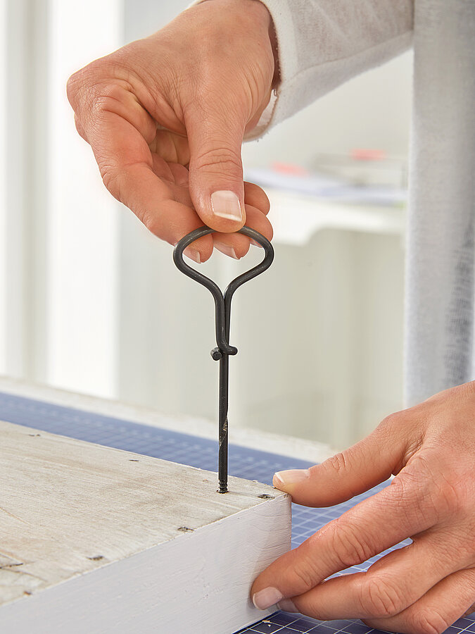 Wanddeko mit Pflanzen in der Vorbereitung, Einschrauben von Ösen in einen Holzrahmen als Basis für eine DIY-Pflanzenwand