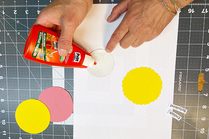 Einschulung Orden basteln mit Kleber und Papierkreisen für die Gestaltung der Ordenmitte