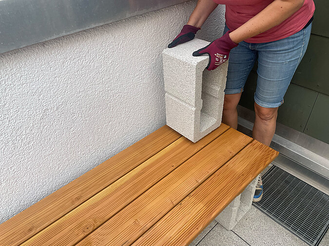 Grillplatz für die Terrasse bauen: Platzieren der zweiten Betonsteinreihe auf der unteren Ablage – wichtiger Montageschritt für die mehrstöckige DIY-Grillstation auf der Terrasse.