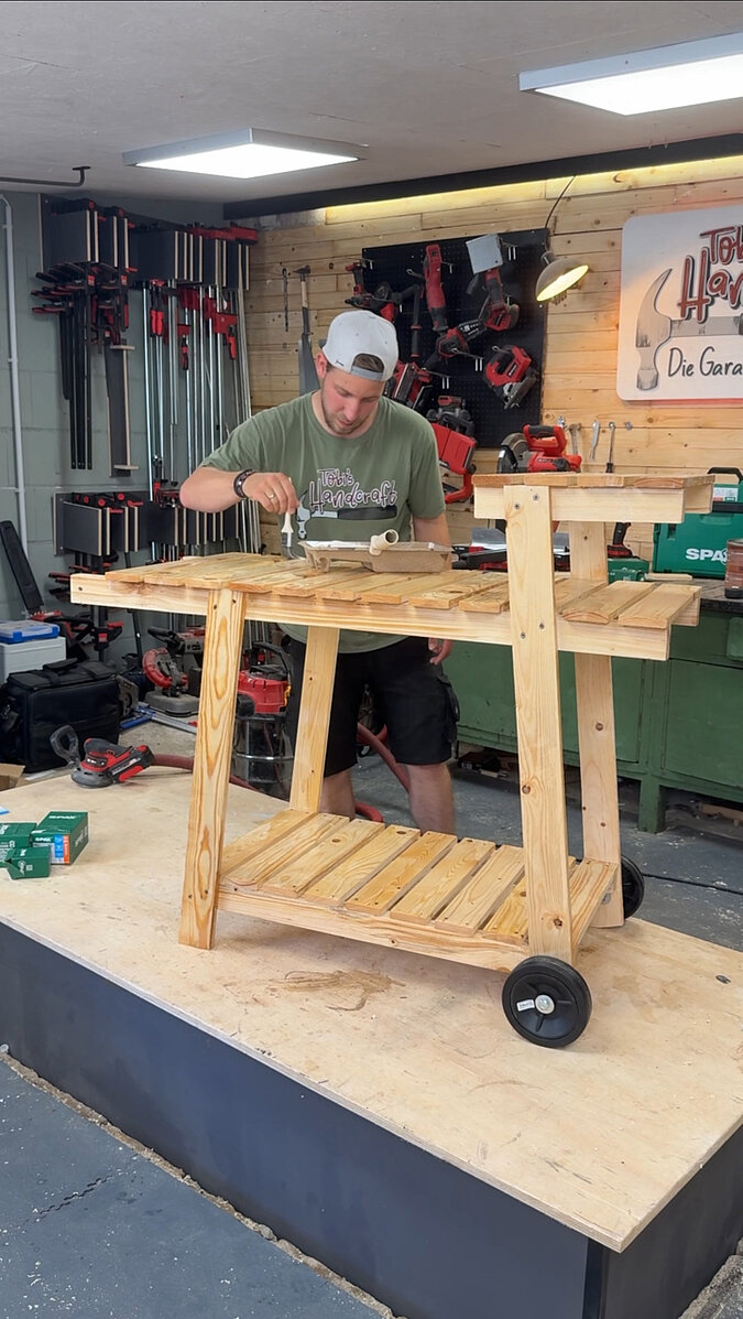 Mobilen Grillwagen bauen beim gleichmäßigen Einölen der Holzflächen mit dem Pinsel, Veredelung der Arbeitsplatte und Ablagen des mobilen Grillwagens