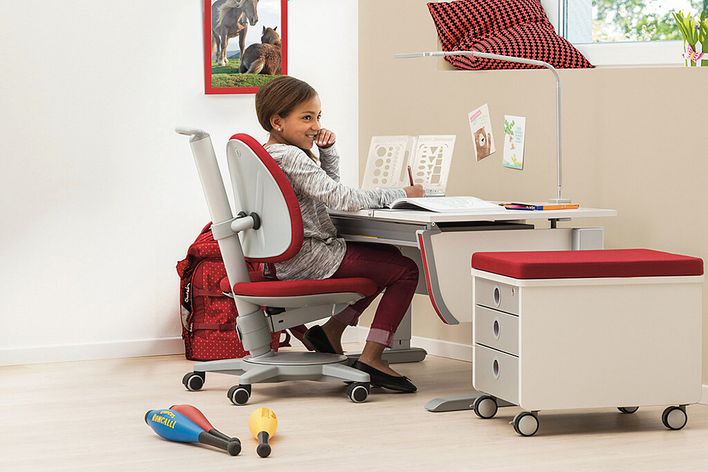 Mädchen sitzt am Schreibtisch auf einem ergonomischen Stuhl