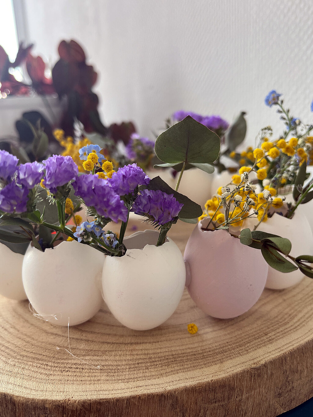 Osterkranz aus Eierschalen basteln mit weiß und pastellfarben bemalten Eierschalen, gefüllt mit lila Blüten, Eukalyptus und gelben Trockenblumen als kreative Osterdeko