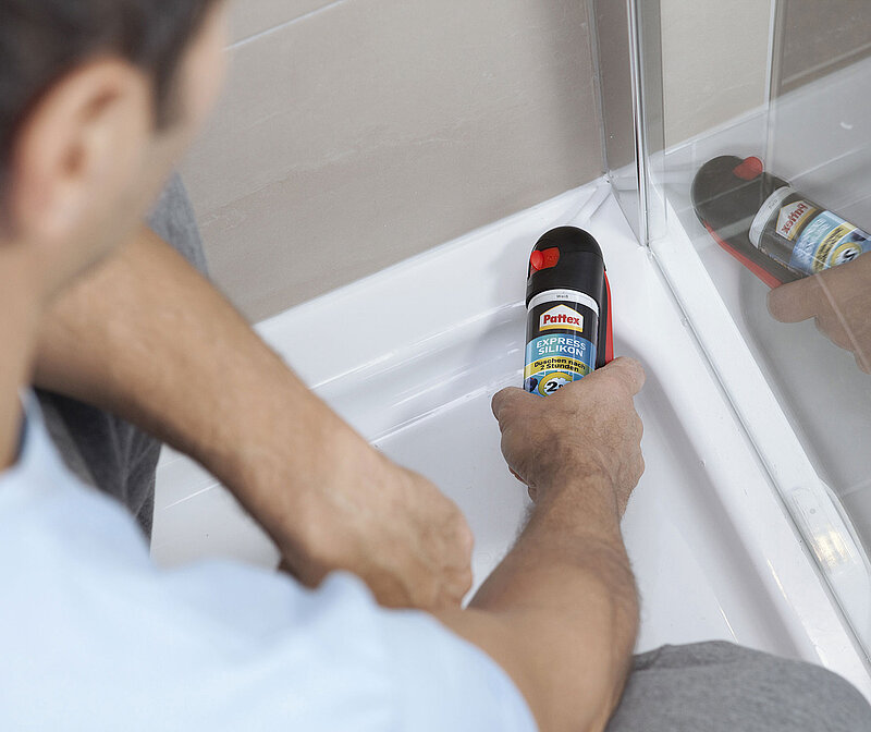 Mann erneuert in Dusche die Silikonfugen neu