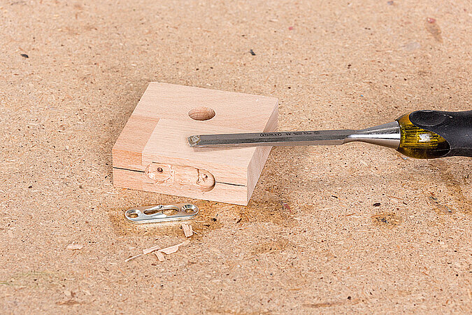 Wandgarderobe aus Kickerfiguren bauen mit Dübel und Schraubendreher beim Montieren des Holz-Abstandshalters für die Wandbefestigung