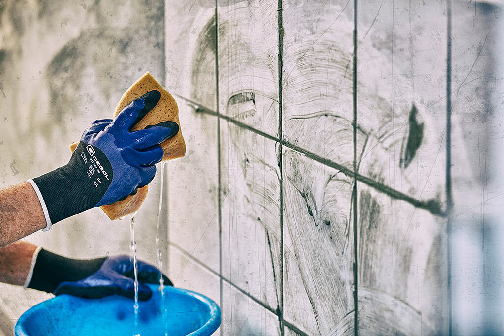 Fliesen an die Wand kleben Reinigung der frisch verfugten Fliesen mit Schwamm und Wasser für ein sauberes Fugenbild