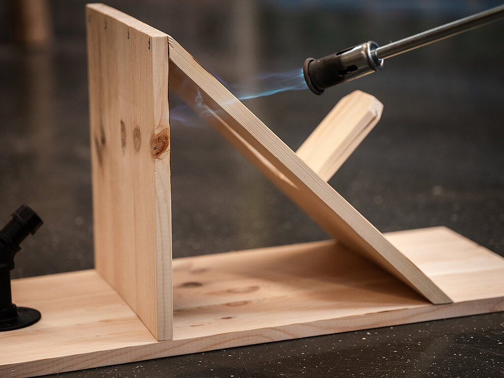 Die Oberfläche einer Holzgardeobe wird mit einem Unkrautbrenner angeflämmt