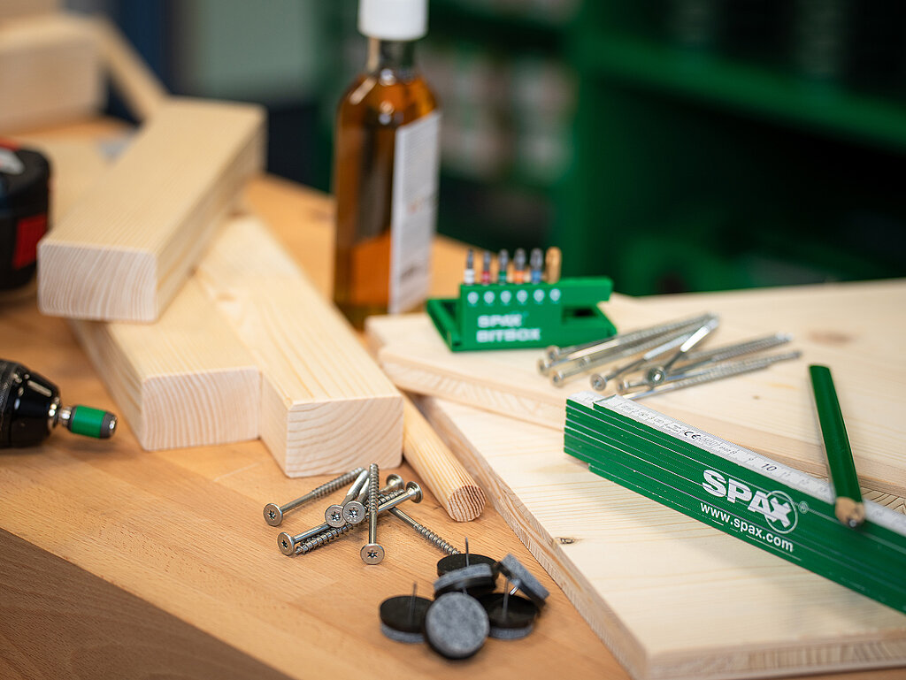Lernturm für Kinder bauen mit sorgfältig vorbereiteten Holzleisten, Schrauben, Dübeln und SPAX-Werkzeug auf einer Werkbank für den DIY-Projektstart