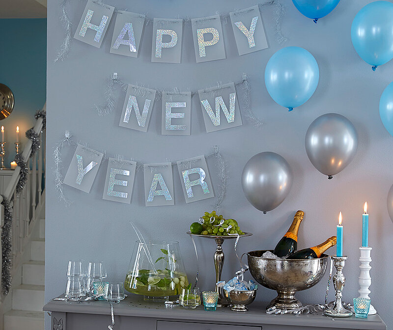 Happy New Year-Girlande, gebastelt aus einzelnen Buchstaben hängt zu Silvester an der Wand