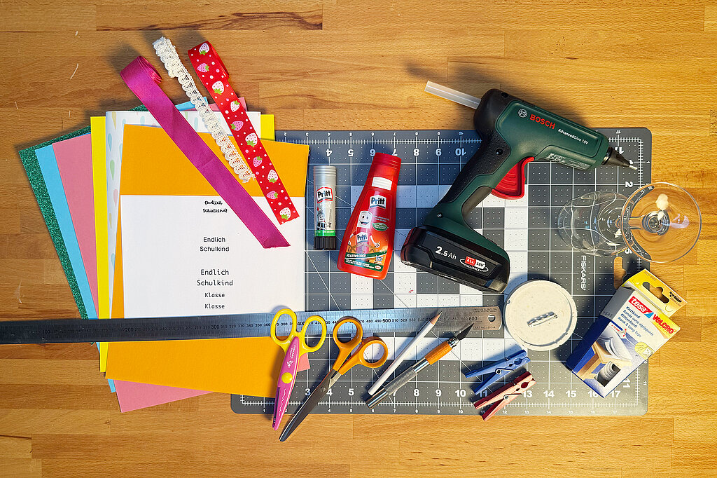 Einschulung Orden basteln mit Bastelmaterialien wie Papier, Schleifenband, Schere und Kleber für kreative Schulkind-Orden