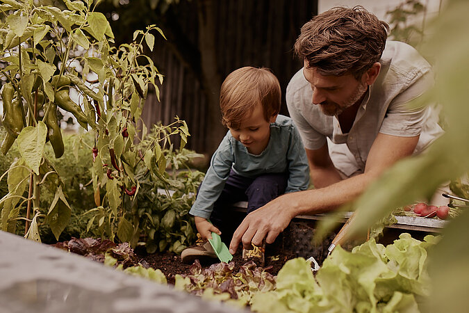 Kind und Mann im Hochbeet
