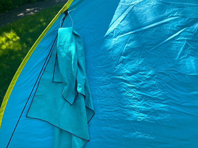 Festival Gadgets nasses Handtuch hängt am Zelt in improvisierter Kabelbinder-Schlaufe
