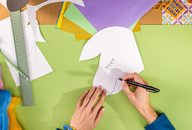 Schultüte Einhorn basteln mit aufgemaltem Gesicht auf der Einhorn-Vorlage aus Papier